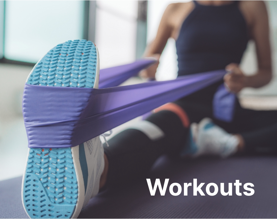 Workouts. A woman in fitness apparel sitting down while using a purple band under her light blue sneakers.
